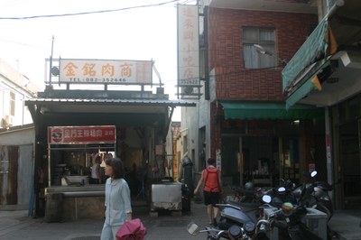 環境 1|章君祖|2010/7/3|：石獅位於小吃店與肉商中的小巷底